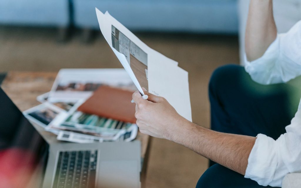 Person checking documents next to a laptop