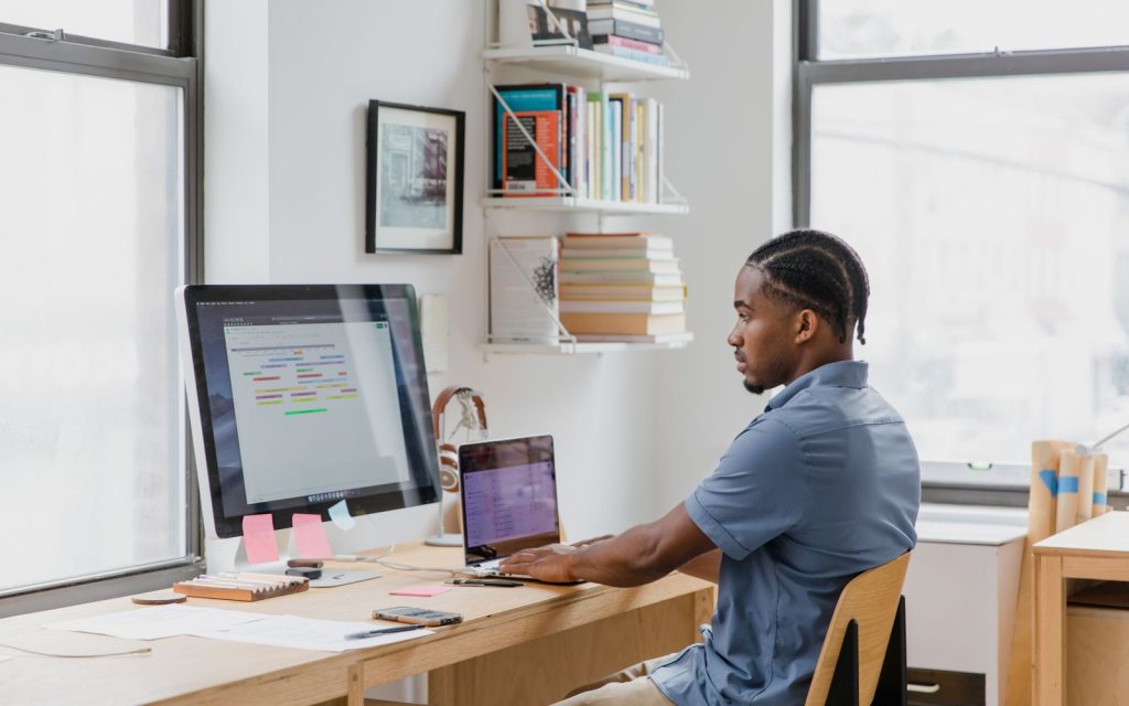 Professional working at a desk with monitor and laptop