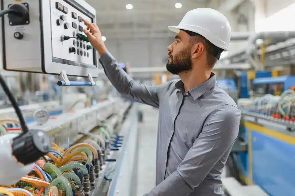Engineer wearing a hard hat operating a control panel in a modern factory